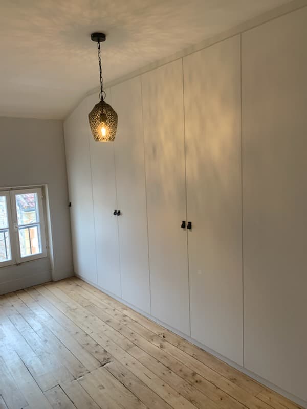 Dressing à portes battantes rose poudré sous comble, réalisé par Maison Gazeau